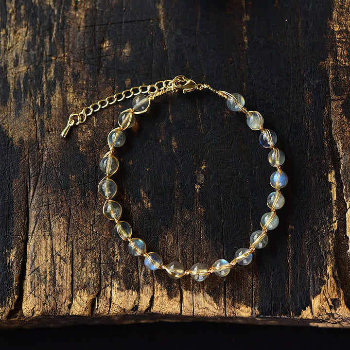 Mondstein Armband mit goldenen Kettendetails auf Holzoberfläche Nahaufnahme