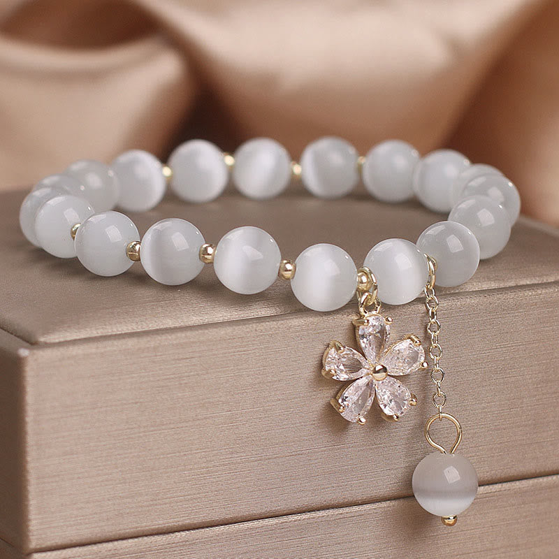 Weißes Jade Armband mit Blütenanhänger und goldenem Schmuck elegant.