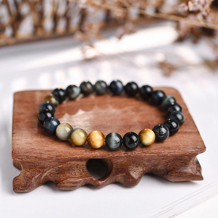 Armband Tigerauge Kristall auf Holzständer schwarze goldene Perlen Heilung
