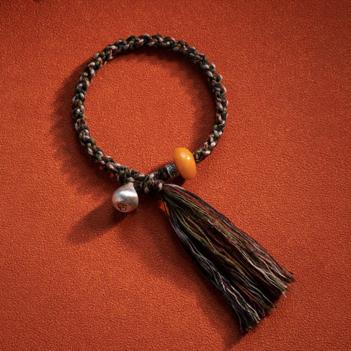 Geflochtenes Armband mit Silberperle und schwarzer Quaste Schutz.