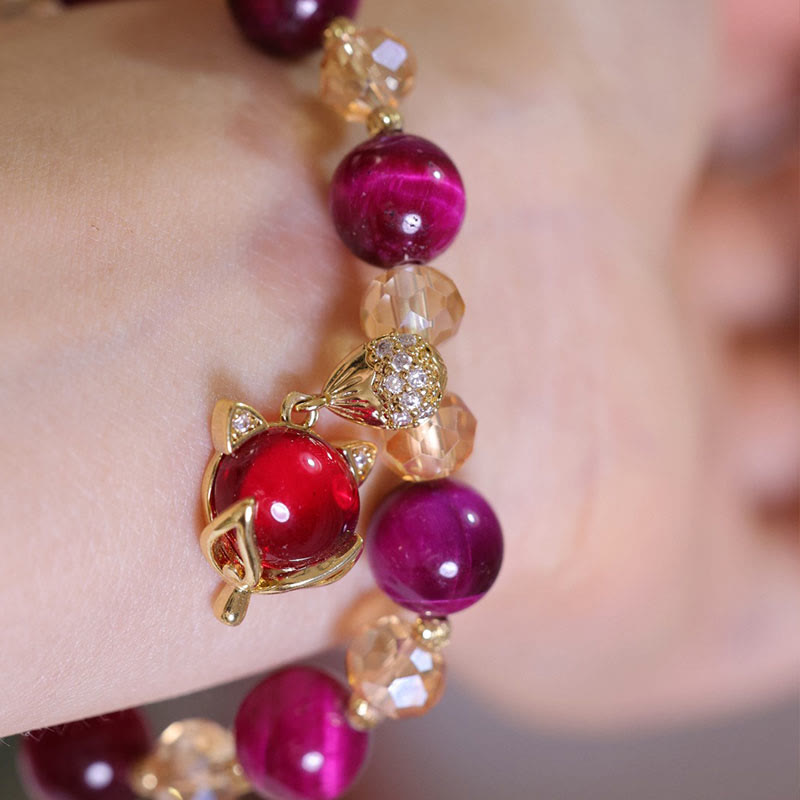 Elegantes Armband mit roten Steinen und goldenem Pixiu-Anhänger am Handgelenk.