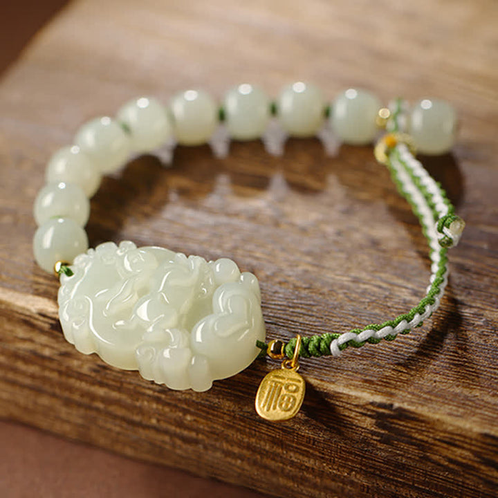 Jade Armband mit geschnitztem Anhänger und grünem Seidenband elegant.