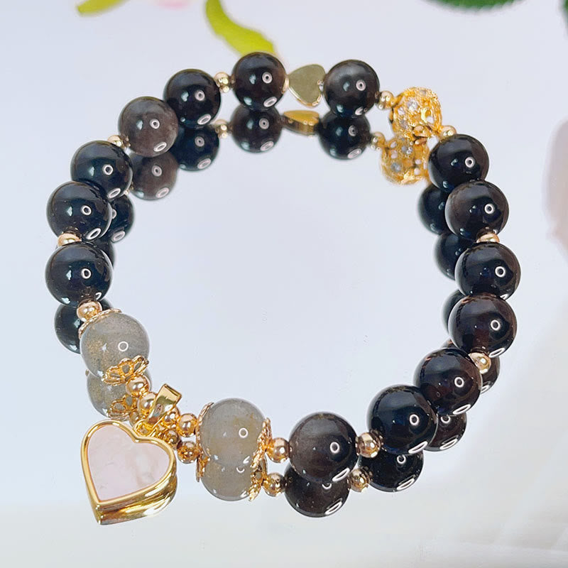 Schwarzes Obsidian Armband mit Herzanhänger und Goldakzenten elegant.