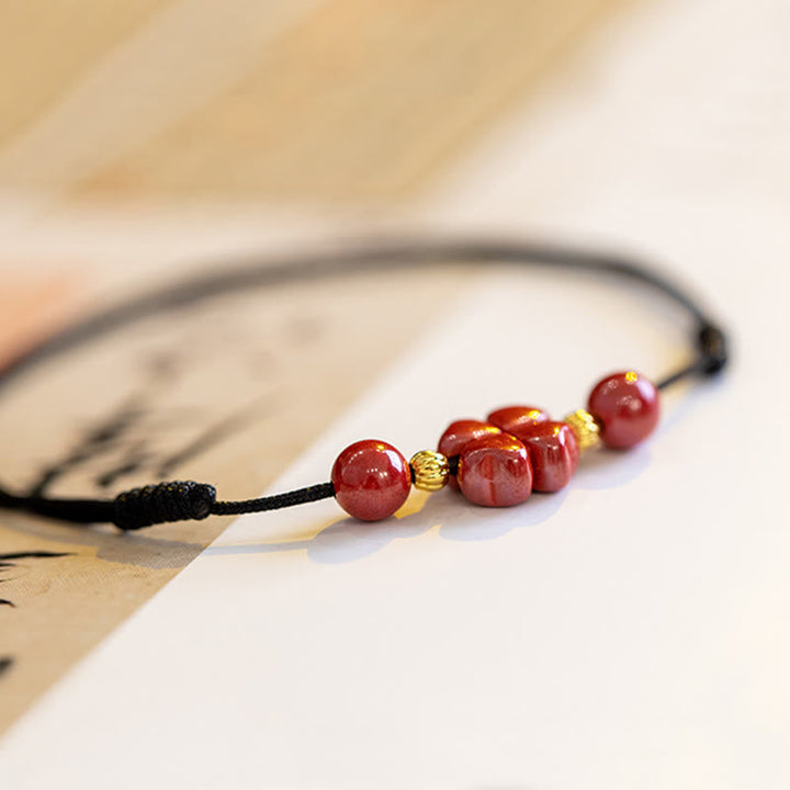 Rotes Armband mit Zinnober Perlen und goldenen Akzenten, elastisch gebunden