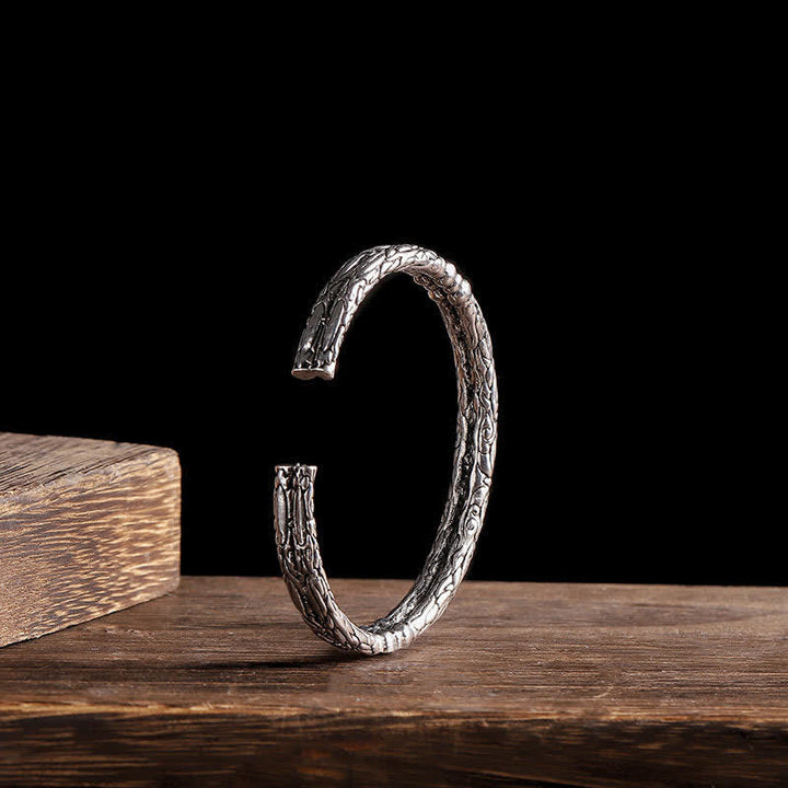 Silbernes Drachen-Armband auf Holz, strukturiertes Design, Balance