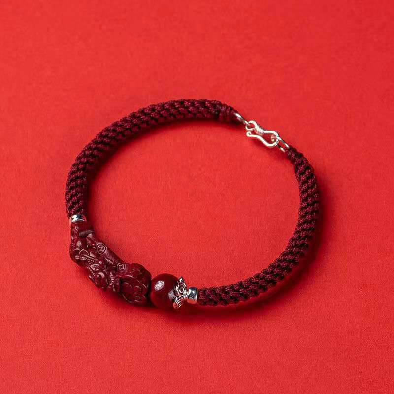 Armband Zinnober Pixiu Glück Wohlstand rotes Textil Flachlage Schmuck