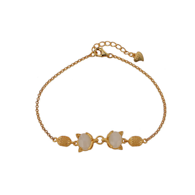 Goldenes Armband mit weißer Jade und Fuchs-Anhängern elegant gestylt.