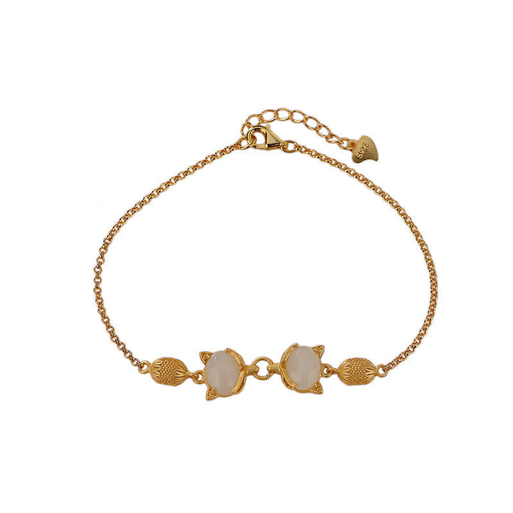 Goldenes Armband mit weißer Jade und Fuchs-Anhängern elegant gestylt.