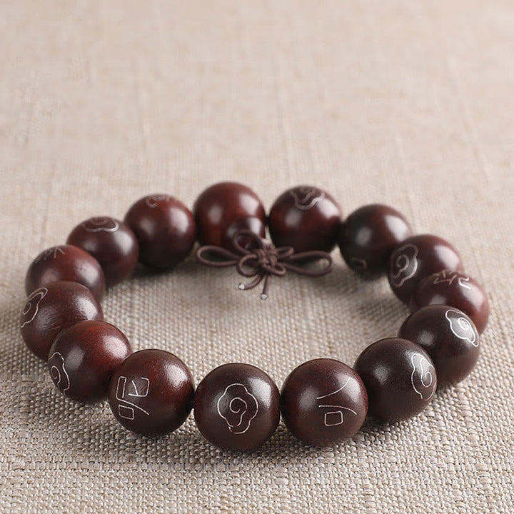 Dunkelbraunes Sandelholz Armband mit Om-Symbolen auf Leinen.