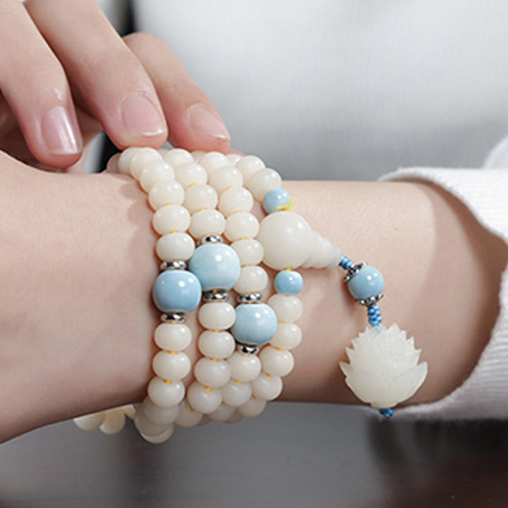 Bodhi Lotus Armband mit weißen Perlen und blauen Akzenten getragen