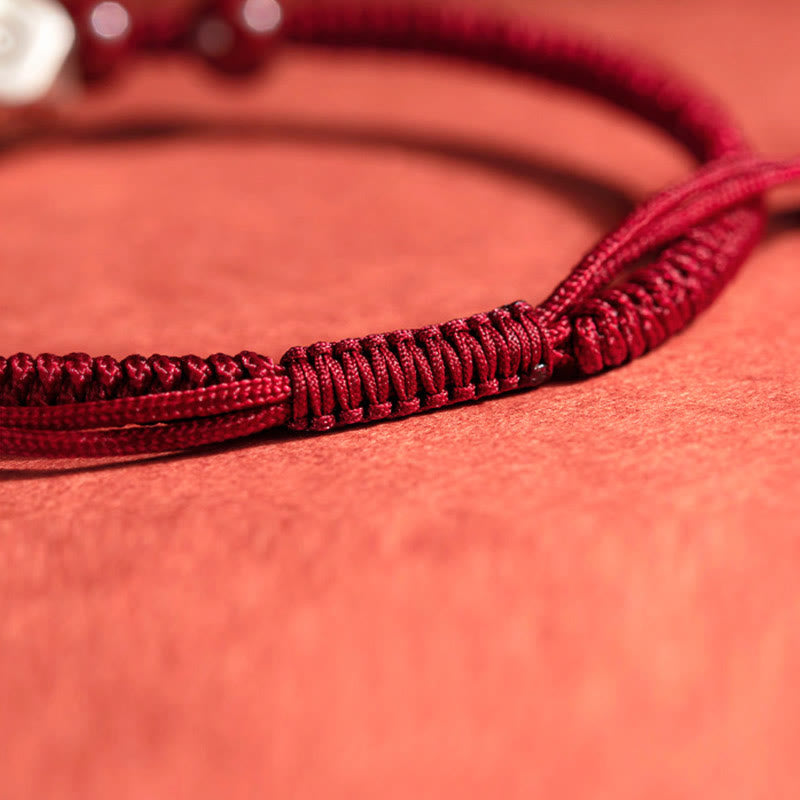 Rotes Armband mit geflochtener Schnur auf korallenfarbenem Hintergrund elegant