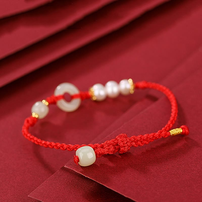 Rotes Armband mit Perlen und goldenem Verschluss elegant präsentiert.