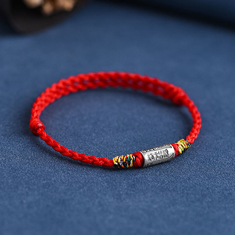 Rotes Armband mit Silber-Element, traditionelles Schutzarmband auf blauem Untergrund.