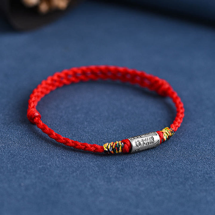 Rotes Armband mit Silber-Element, traditionelles Schutzarmband auf blauem Untergrund.