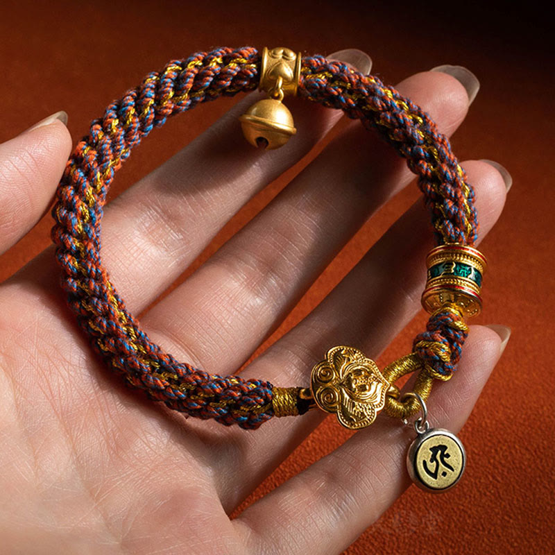 Buntes Armband mit goldenen Om-Anhängern an der Hand getragen.