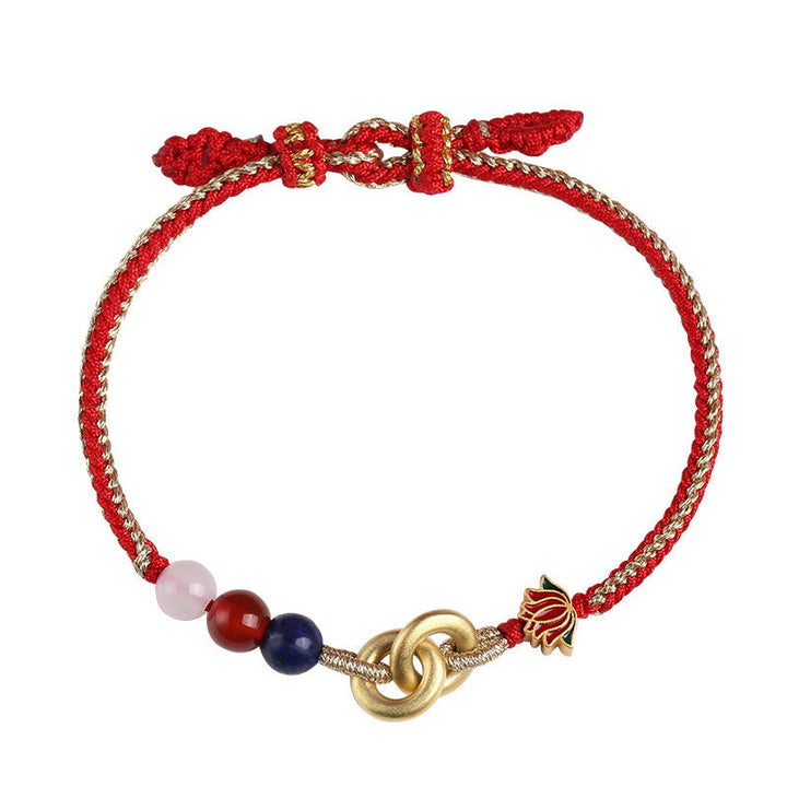 Rotes Armband mit Lotus-Charm und Perlen elegant präsentiert.
