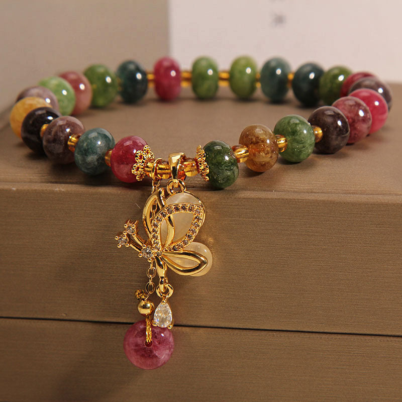 Armband Schmetterling mit bunten Edelsteinen und goldenem Verschluss.
