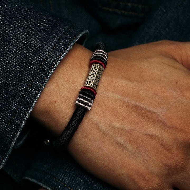 Armband 925 Silber Om Mani Padme Hum am Handgelenk mit schwarzem Textil und roten Akzenten getragen