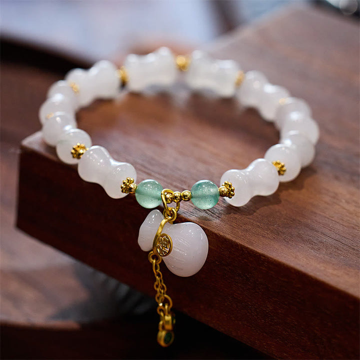 Weißes Jade Armband mit grünen Steinen und goldenem Fu-Zeichen Anhänger.