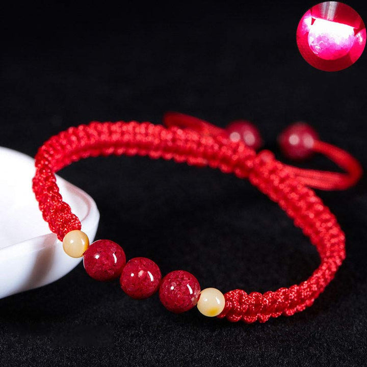 Rotes Armband Zinnober – Segen mit Perlen auf schwarzem Hintergrund