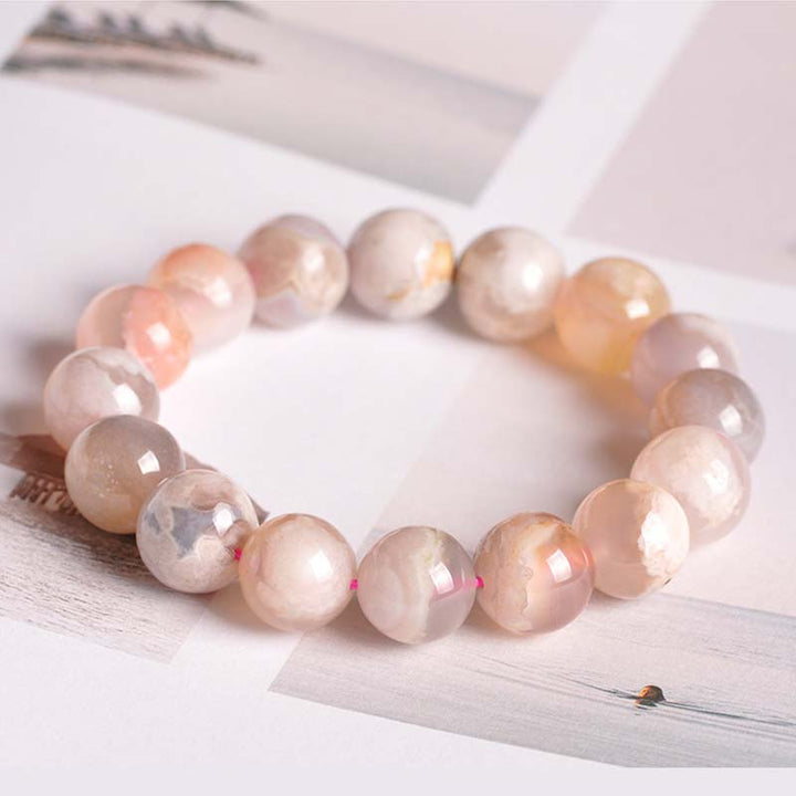 Rosafarbenes Achat Armband mit facettierten Perlen, flach präsentiert auf weißem Untergrund.