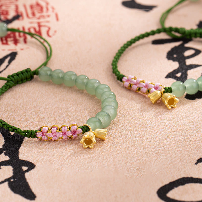 Jade Armband mit grünen Steinen, rosa Blüten und goldenen Elementen.