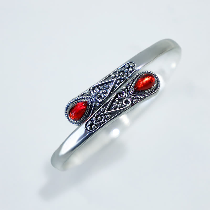 Silbernes Armband mit roten Steinen ornamental verziert Nahaufnahme