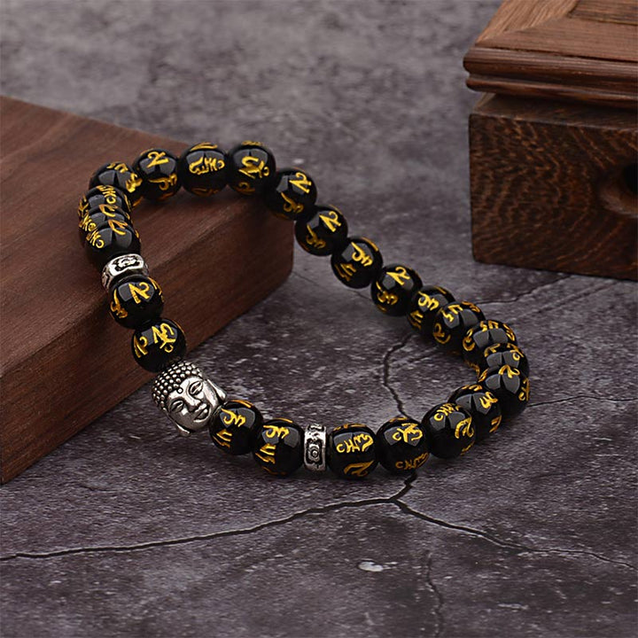 Armband Tibet Buddha Mantra Amulet schwarze Perlen goldene Schrift Holz Hintergrund