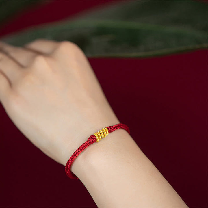 Rotes Armband – Schutz & Glück Energie mit goldfarbenen Elementen am Handgelenk