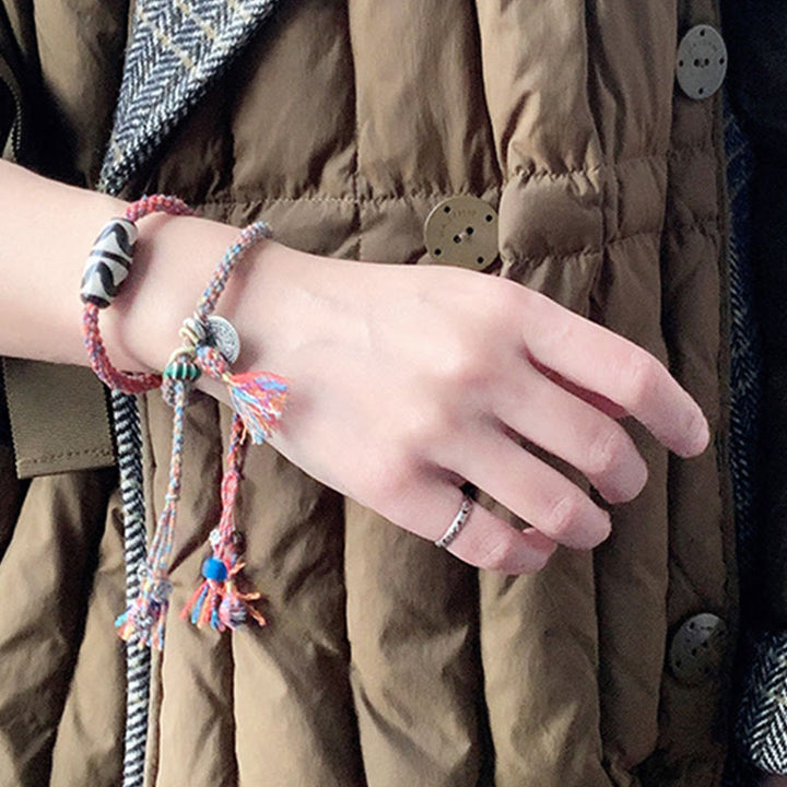 Bunte Armbänder am Handgelenk mit Quasten und Perlen getragen.