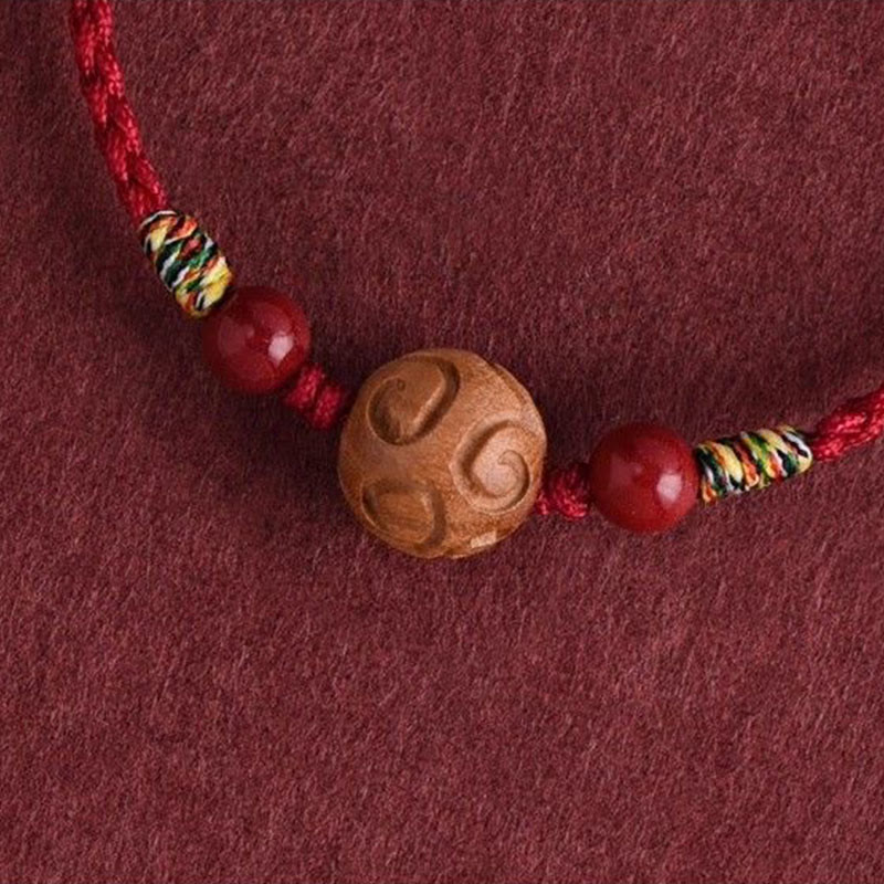 Armband Pfirsichholz Zinnober – Glück mit geschnitzter Holzperle und rotem Band