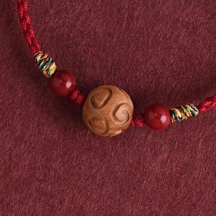 Armband Pfirsichholz Zinnober – Glück mit geschnitzter Holzperle und rotem Band