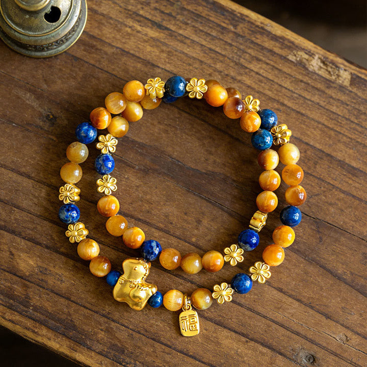 Armband Lapislazuli Tigerauge Fu-Zeichen mit goldenem Pixiu Anhänger auf Holz