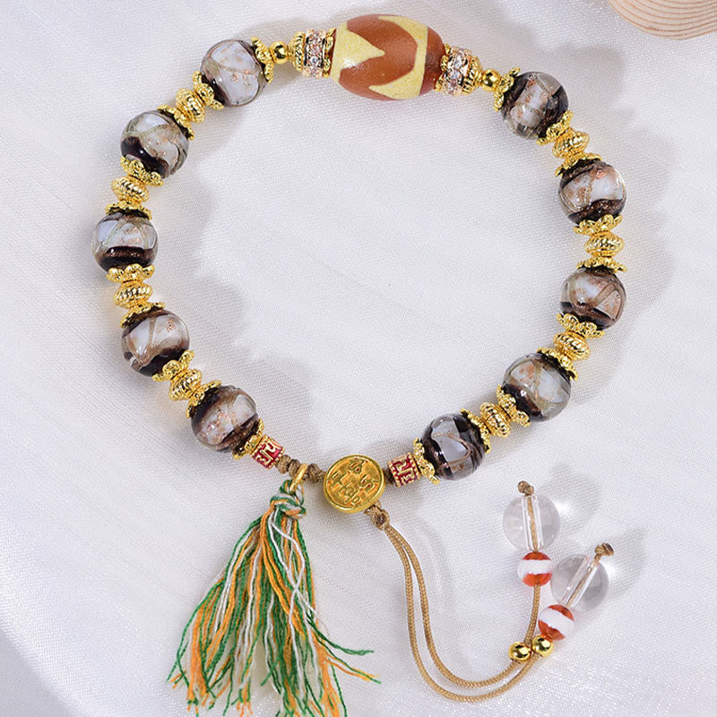 Armband Liuli – Segen mit Dzi Perle goldenen Akzenten und Quaste am Handgelenk