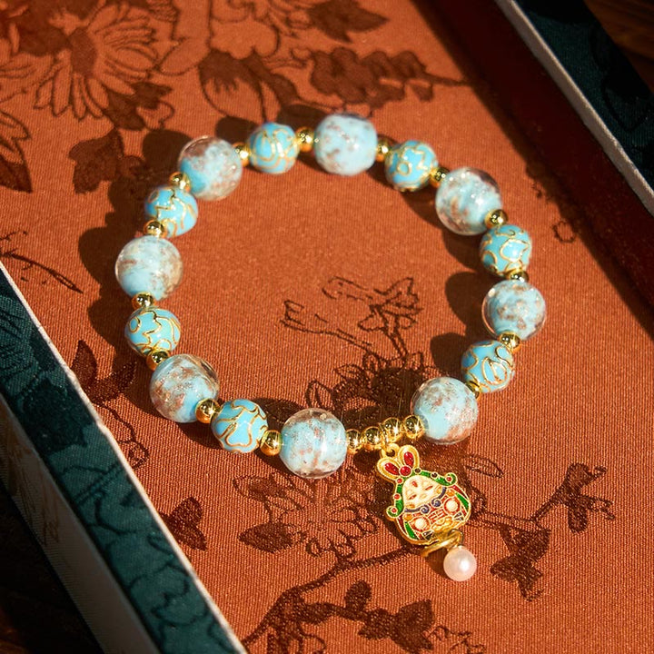 Armband Liuli Hase – Glück mit hellblauen Perlen und goldenem Hasenanhänger im Schmuckkästchen
