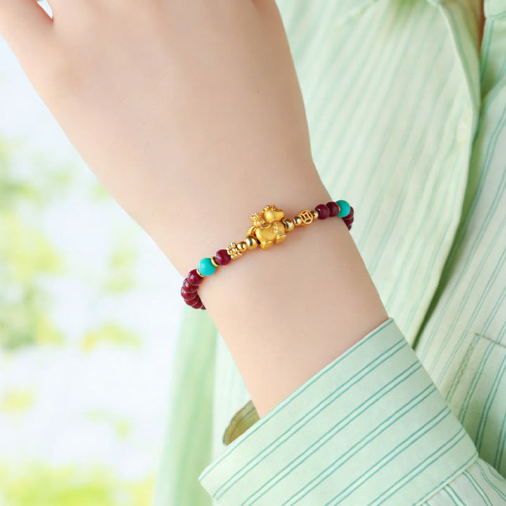Armband Zinnober Fu-Zeichen Ruhe Energie goldener Anhänger Türkis Handgelenk getragen