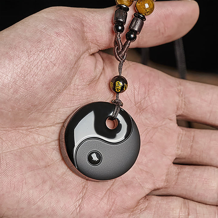 Schwarzer Obsidian Kette Yin Yang Anhänger in Hand getragen Naturstein