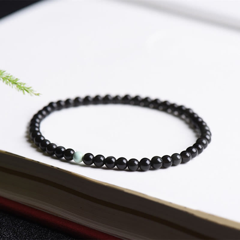 Armband Schwarzer Obsidian Türkis Stärke Perlen auf Buch elegant
