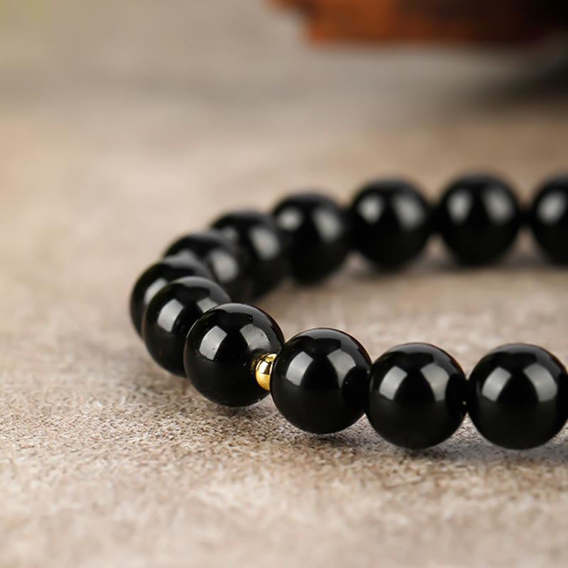 Armband Schwarzer Obsidian Stärke glänzende Perlen goldener Akzent Schutz Handgelenk