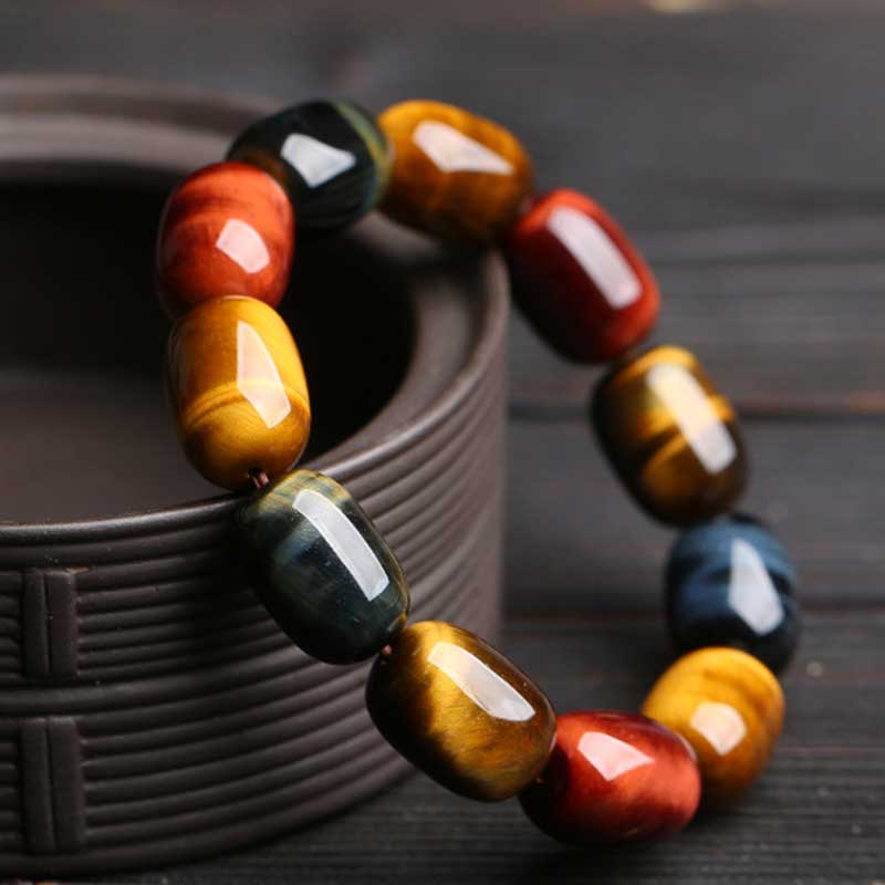 Armband Tigerauge Schutz Heilung buntes Perlenarmband auf Holzschale Nahaufnahme