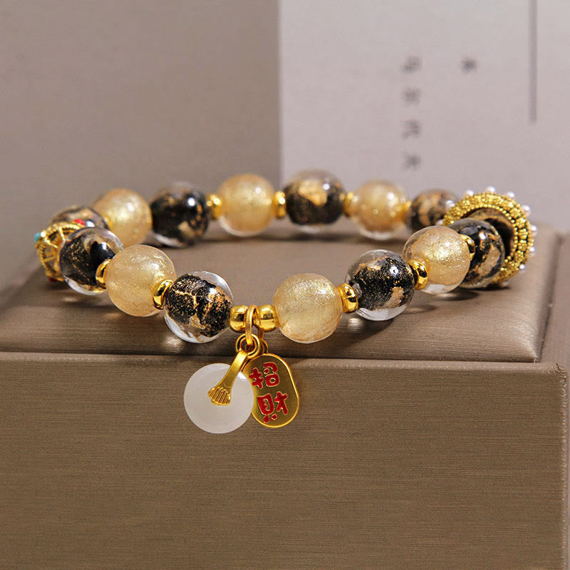 Armband Liuli – Wohlstand & Frieden mit goldenem Glücksanhänger auf Schmuckbox