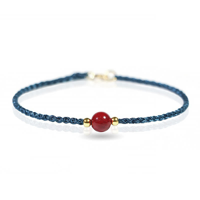 Armband Zinnober Rotes Band mit Goldperlen filigran am Handgelenk getragen