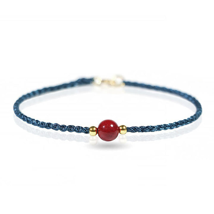 Armband Zinnober Rotes Band mit Goldperlen filigran am Handgelenk getragen